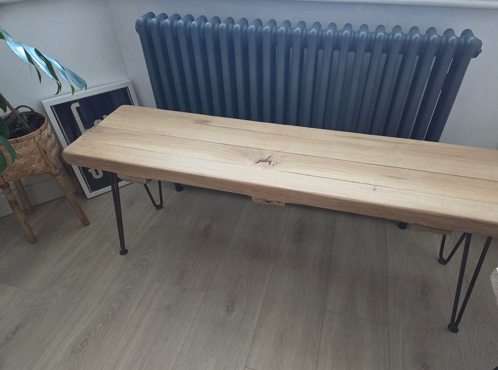 A real oak bench with metal legs placed on a wooden floor.